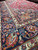 Raised angle across a rose red field and navy border with floral and paisley motifs