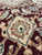 Close-up of a salmon and ivory palmette cartouche set against the burgundy border ground