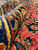 Close-up of thick wool pile folded back, revealing navy, gold and coral hand-knotted floral detail