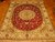 Red and ivory hand-knotted wool rug laid flat across golden parquet flooring indoors