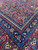 Angled close-up of layered borders, orange guard band and burgundy field of antique rug
