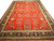 Full view of 14' x 24' oversize Sarouk design rug with red field and black floral border
