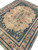 Corner perspective of the hand-knotted wool rug with navy vine border and muted salmon guard stripes