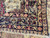 Folded corner revealing multiple guard borders, camel ground and hand-knotted wool weave of the antique rug