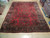 Red Sarouk rug laid flat on showroom floor showing full all over floral design and borders