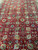 Close-up of the red field showing palmettes, rosettes and vine scrolls in green, ivory and sky blue