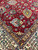 Corner detail of the ivory main border with golden guard stripes meeting the crimson floral field