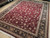 Angled view showing black floral main border, ivory guard stripes and dense burgundy floral field