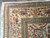 Corner detail of ivory floral border, layered guard stripes and white fringe on wool rug
