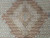 Macro of the stepped rust central medallion with fine wool and silk outlining