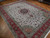 10x13 wool and silk Tabriz rug at an angle, coral border with salmon corner cartouches visible