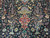 Blossoming trees, pheasants and a burgundy pendant medallion woven into the deep navy blue field