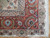 Corner detail showing coral border, ivory guard stripe and clean hand-tied fringe on parquet flooring
