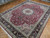 Angled view of red wool and silk Tabriz rug showing dense floral field and corner spandrels