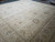 Angled view of the palace size square rug showing corner resolution and wide wheat border