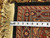 Tape measure laid across the burgundy border verifying scale beside the ivory hand-tied fringe
