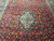 Hand-knotted wool medallion and dense floral field photographed from above in natural warehouse light