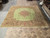 13x14 square Persian rug laid flat in the warehouse, green field and rose garland border