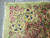 Close-up of ivory fringe and border corner with pink blossoms on pale green wool pile