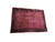 Angled studio shot showing navy blue borders framing the rose red Kashan floral field