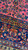 Vertical close-up of border and field junction with sapphire blue ground and crimson blossoms