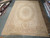 11'10" x 18' Aubusson rug displayed flat on showroom floor beside rolled inventory rugs