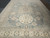 Large 10x15 wool area rug photographed from one end, pale blue field with beige borders