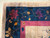 Corner detail of navy border with burgundy, purple and gold blossoms beside pink guard stripe