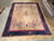 Large 11x14 Art Deco area rug displayed beside other hand-knotted rugs in the warehouse