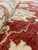 Close-up of soft natural wool pile showing orange red abrash and cream vine scrollwork