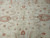 Close-up of ivory wool pile with coral rosettes and soft sage leaf vines across field