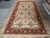 Oversize 9 x 18 hand-knotted wool rug displayed on stone showroom floor with ivory field