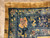 Corner detail showing navy border, gold dragon scrollwork, pink blossoms and two small woven marks