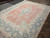 Angled showroom view of the 10x13 vintage Kerman, salmon field fading into ivory cornerwork