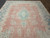 Low pile vintage Persian rug showing ivory floral clusters, faded rose ground and denim blue border