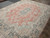 Angled view highlighting soft salmon field, slate blue main border and ivory corner spandrels