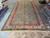 10' x 19'5" oversize Indian rug displayed in showroom with rolled rugs along both sides