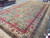 Hand-knotted oversize rug photographed from the corner, ivory guard borders and deep green outer edge visible