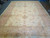 Mansion size Oushak rug seen straight on, pale gold field with pink leafy wreath motifs