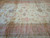 Soft pink border and ivory field with faint storage fold lines across the wool pile