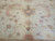 Close up of brown stepped diamond medallion framed by pink leaf wreaths on ivory