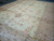 Diagonal warehouse view of the oversize wool Oushak, ivory field framed by pink border