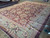 Angled corner shot showing sage green border, salmon guard stripes and thick even wool pile