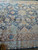 Close view of burgundy scrolling vine border and sage guard bands on wool silk pile