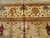 Detailed border photograph showing gold palmettes, rosettes and brown leaf forms on pale ivory ground