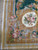 Detailed needlepoint corner with acanthus scrolls, cabbage roses and ivory medallion on dark green ground