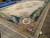 Oversize French Aubusson design rug laid out in the warehouse beside blue rolled rug inventory