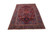 6'5 x 9'10 Heriz rug photographed at an angle on white, showing red field and navy border