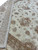 Detail of terracotta rosette, cloudband scrolls and soft brown vines on a cream wool field