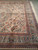 Corner view of ivory Oriental rug showing flower basket border and rose and blue floral field